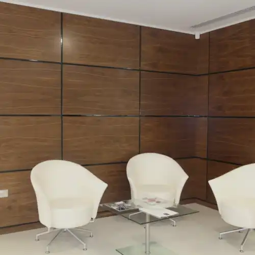 Stylish wall panel made of non-porous veneers, paired with white small sofa chairs for a modern interior look.
