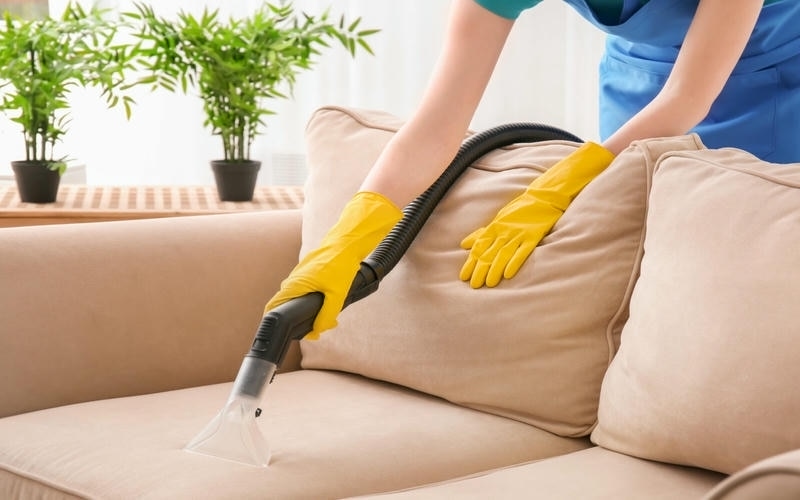 cleaning couch with vacuum cleaner at home